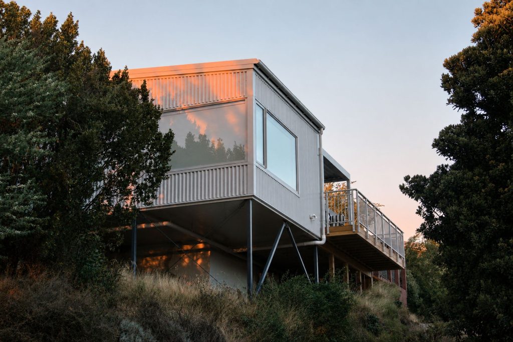 The Huntsbury Treehouse addition at dawn, clad in corrugated steel and raised on slender columns among the trees
