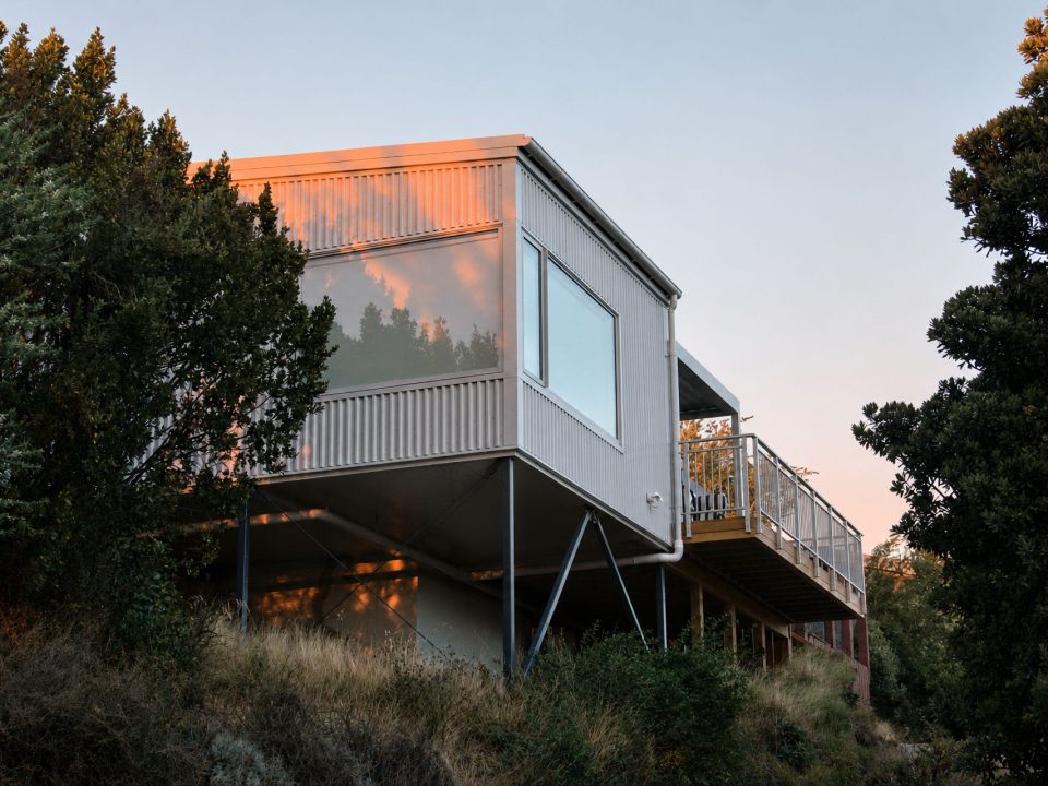 The Huntsbury Treehouse addition at dawn, clad in corrugated steel and raised on slender columns among the trees