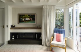 Sitting room with fireplace and soft drapery, opening through French doors to a sheltered deck and garden.