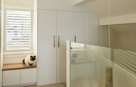 Upper landing with built-in cabinetry and window seat, looking down through glass to the pendant in the stairwell.