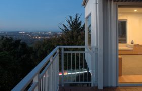 The deck at dusk, looking out over the city lights with the living space glowing behind