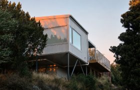 The Huntsbury Treehouse addition at dawn, clad in corrugated steel and raised on slender columns among the trees