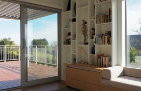 Living space with sliding doors open to a louvred deck, built-in shelving and an oak window seat